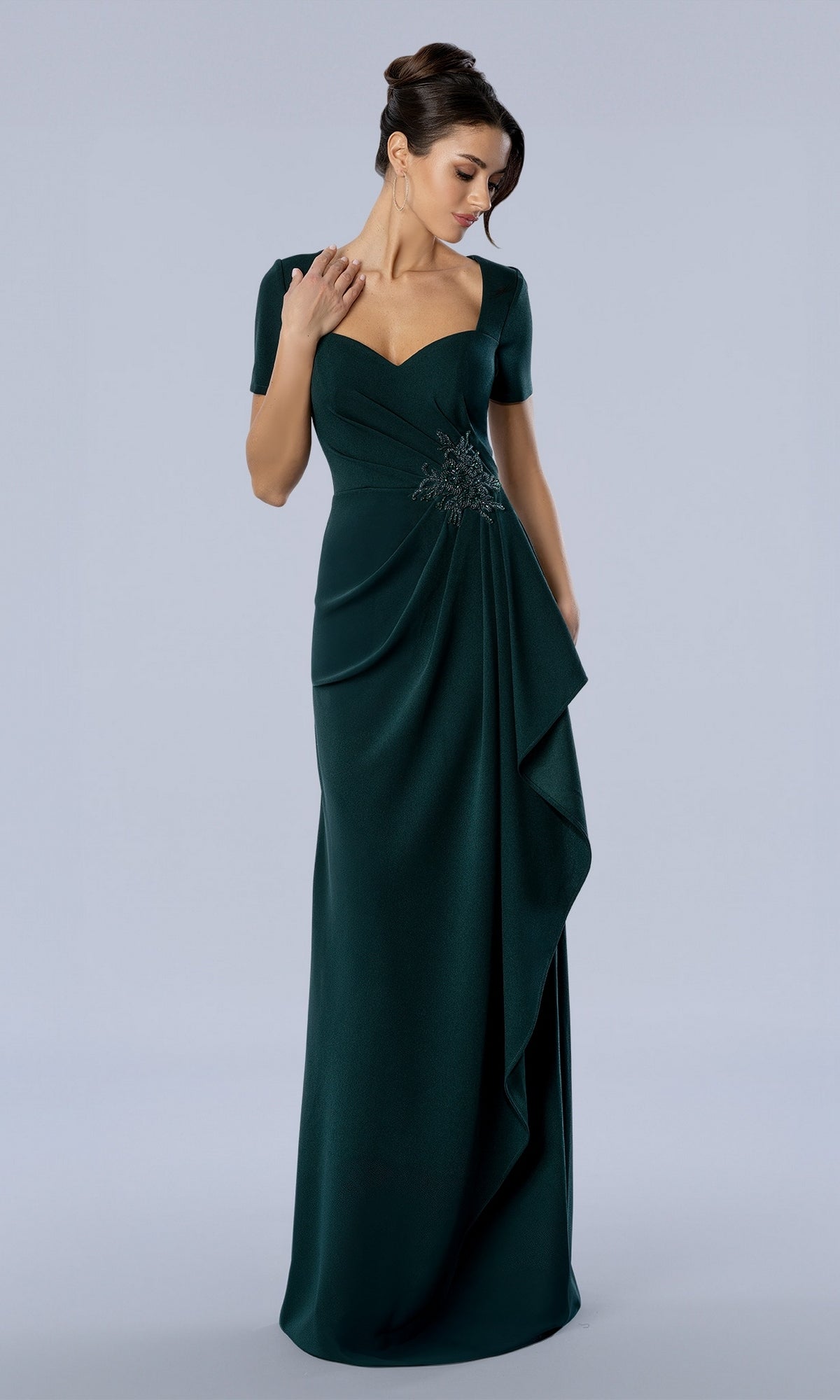 Stella Couture 26376 emerald green evening gown with short sleeves, a sweetheart neckline, and beaded detail on the draped waist.